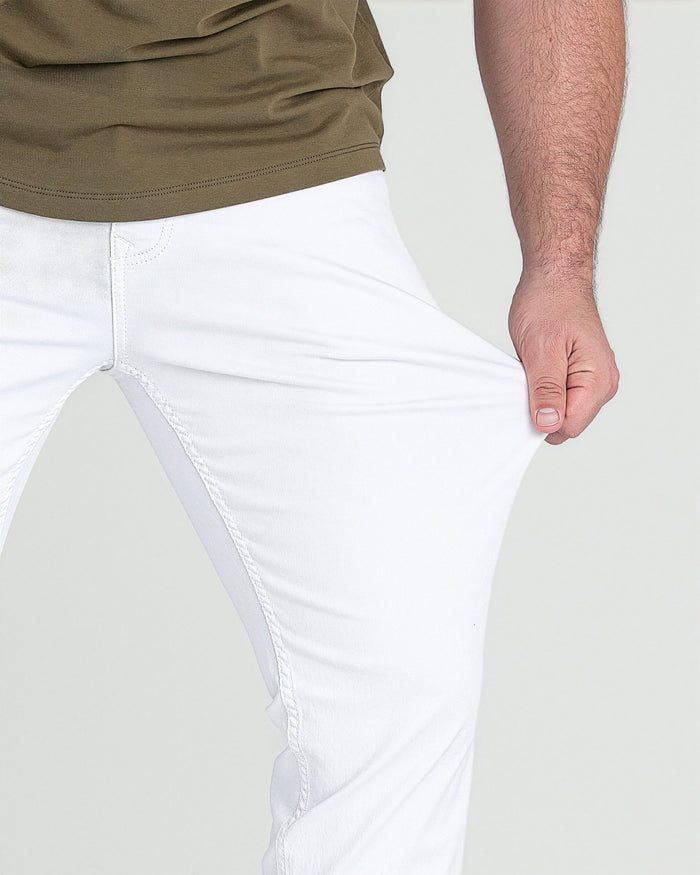 White slim-fit pants with stitched seams, worn with olive-colored shirt.