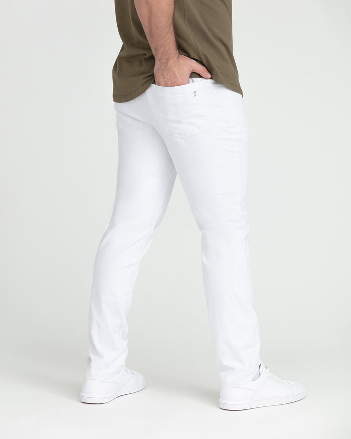 White slim fit jeans with tapered leg on male model wearing olive shirt and white sneakers.