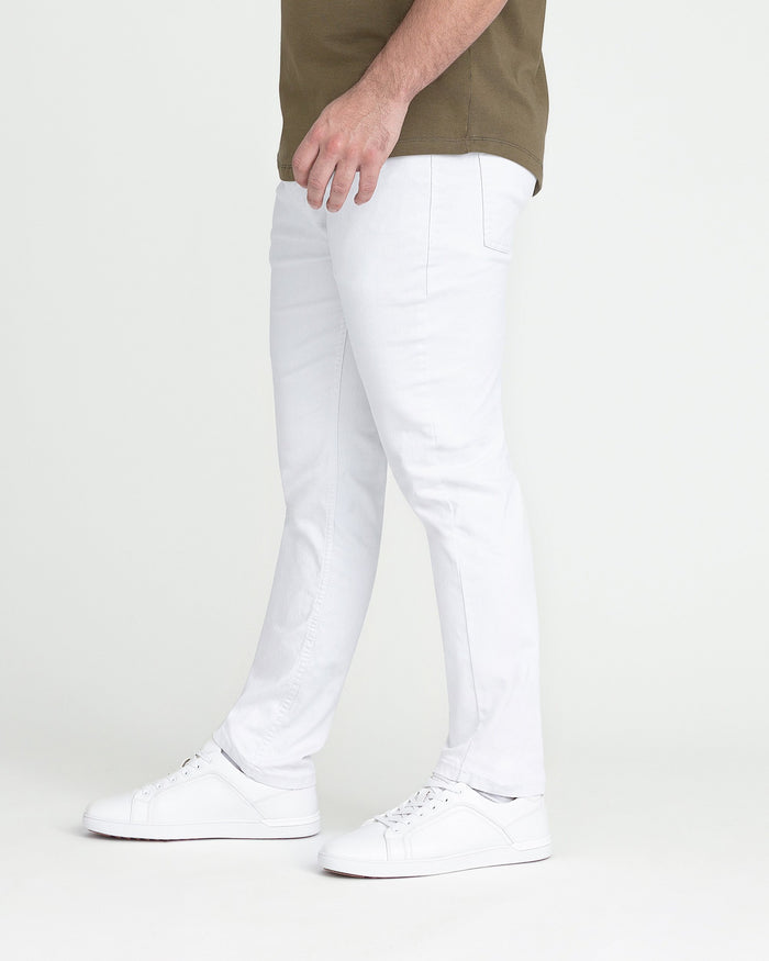 White slim fit jeans with back pocket, paired with olive shirt and white sneakers.