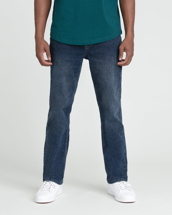 Man wearing midnight blue jeans with teal shirt and white sneakers.