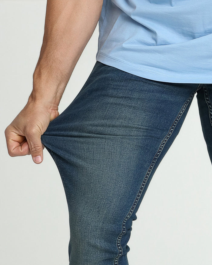 Man wearing light blue t-shirt and dark tinted denim jeans with fitted thigh.