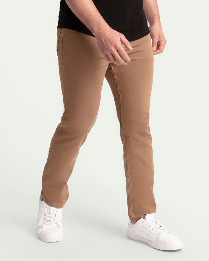 Man wearing dark khaki slim fit pants with black shirt and white sneakers.