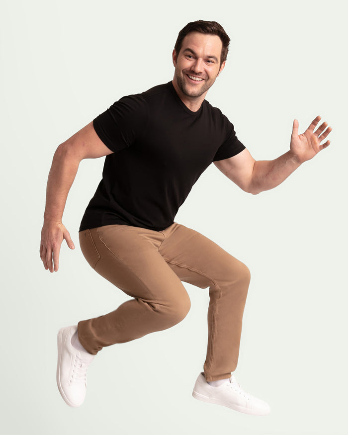 Man wearing black t-shirt and dark khaki slim fit pants with white sneakers.