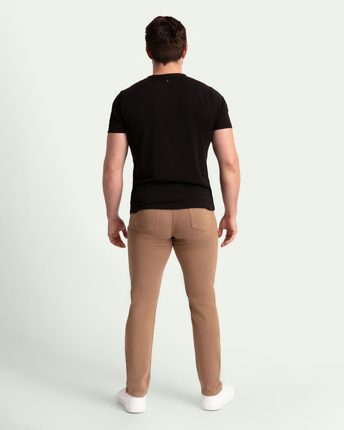 Man wearing black short-sleeve t-shirt and dark khaki slim fit pants, shown from behind.