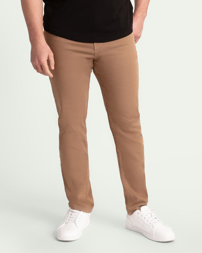 Man wearing dark khaki slim fit pants with black shirt and white sneakers.