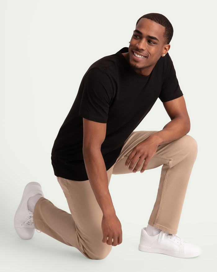 Light khaki slim fit pants worn with black short-sleeve shirt and white sneakers.
