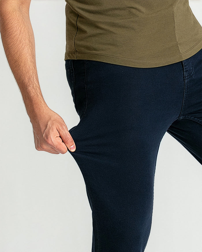 Man wearing olive-green t-shirt and navy slim-fit jeans with visible stitching detail.