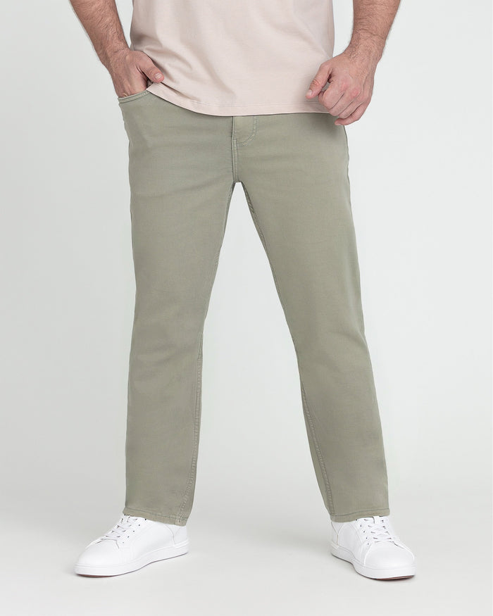 Man wearing light green slim fit chino pants with cream t-shirt and white sneakers.