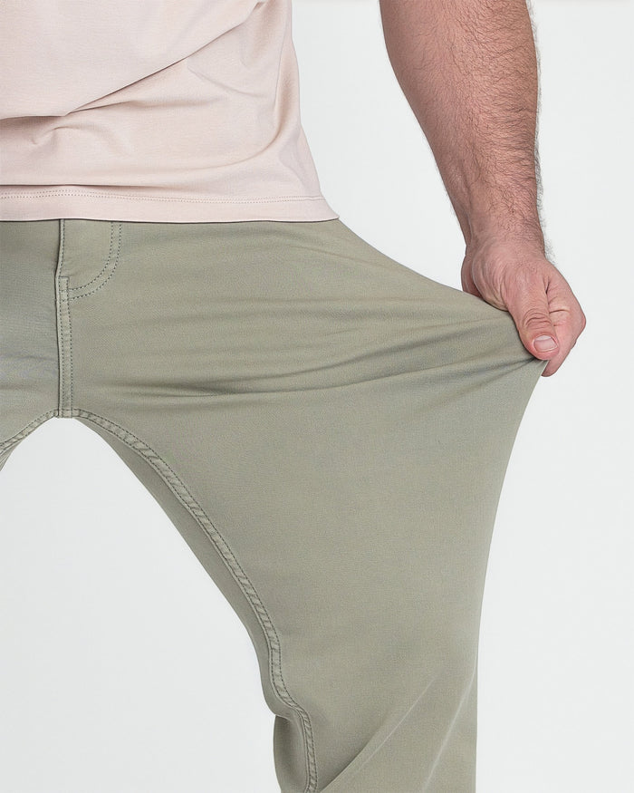 Man wearing light green slim fit pants with beige shirt, showing fit at waist and thigh.