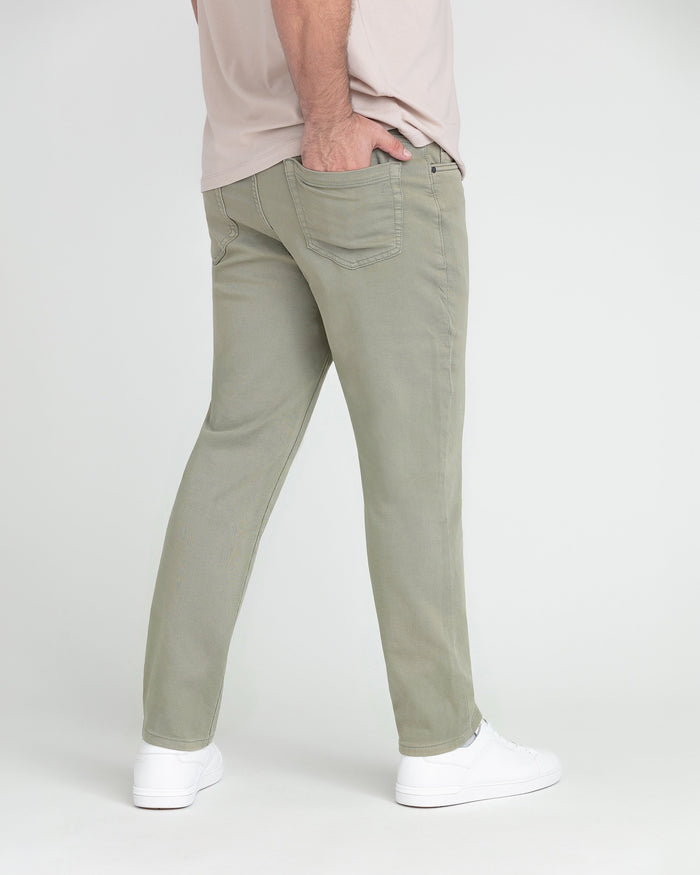 Light green slim-fit pants with visible stitching and pocket details, paired with white sneakers and a beige shirt.