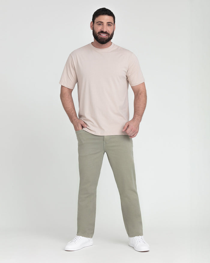 Man wearing light green slim fit pants with a beige crew neck short-sleeve t-shirt and white sneakers.
