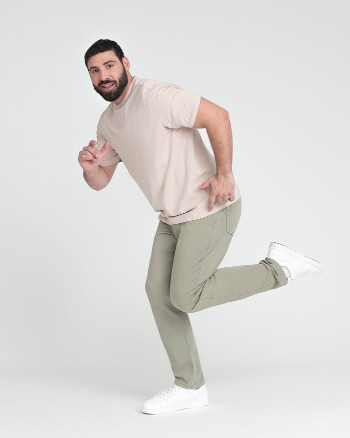 Man wearing beige short-sleeve t-shirt and light green pants with white sneakers.