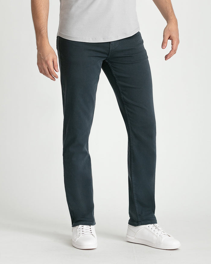 Man wearing light gray t-shirt and dark slate slim-fit jeans with white sneakers.