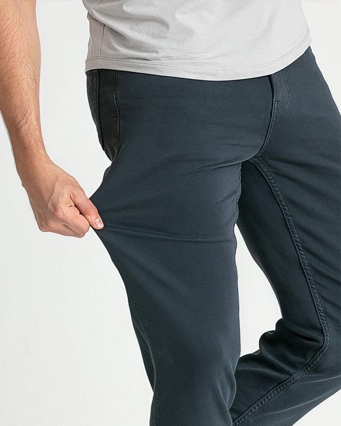 Man wearing slate-colored slim fit jeans with white t-shirt, shown from waist down.