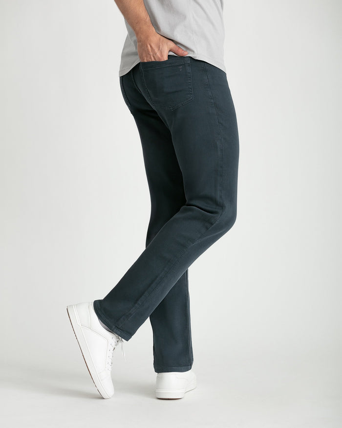 Man wearing slate-colored slim fit jeans with white sneakers and light gray t-shirt.
