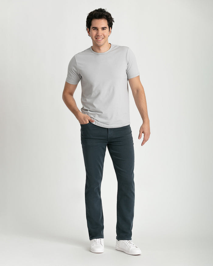 Man wearing light gray short-sleeve t-shirt and slate-colored slim fit jeans with white sneakers.