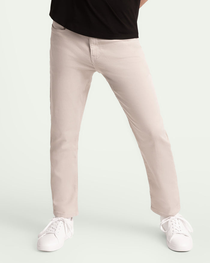Light grey slim fit pants on a model wearing a black top and white sneakers.