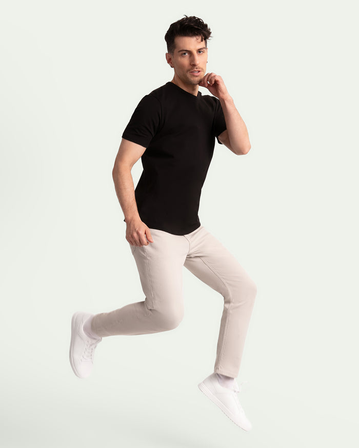 Man wearing black short-sleeve t-shirt and light grey slim fit pants with white sneakers.