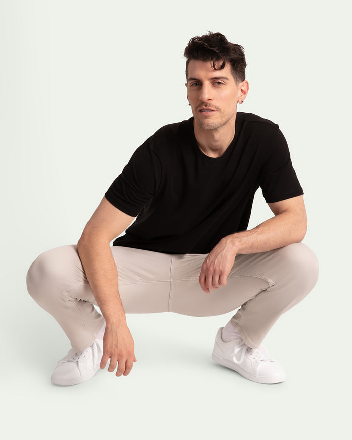 Man wearing black short-sleeve t-shirt and light grey slim fit pants with white sneakers.