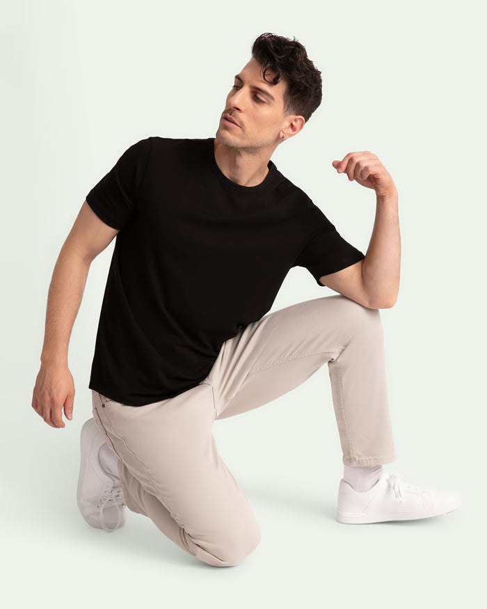 Man wearing black short-sleeve t-shirt and light grey slim fit pants with white sneakers.