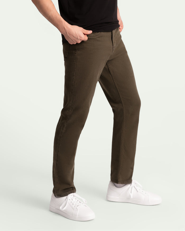 Man wearing olive-colored slim fit pants with black shirt and white sneakers.