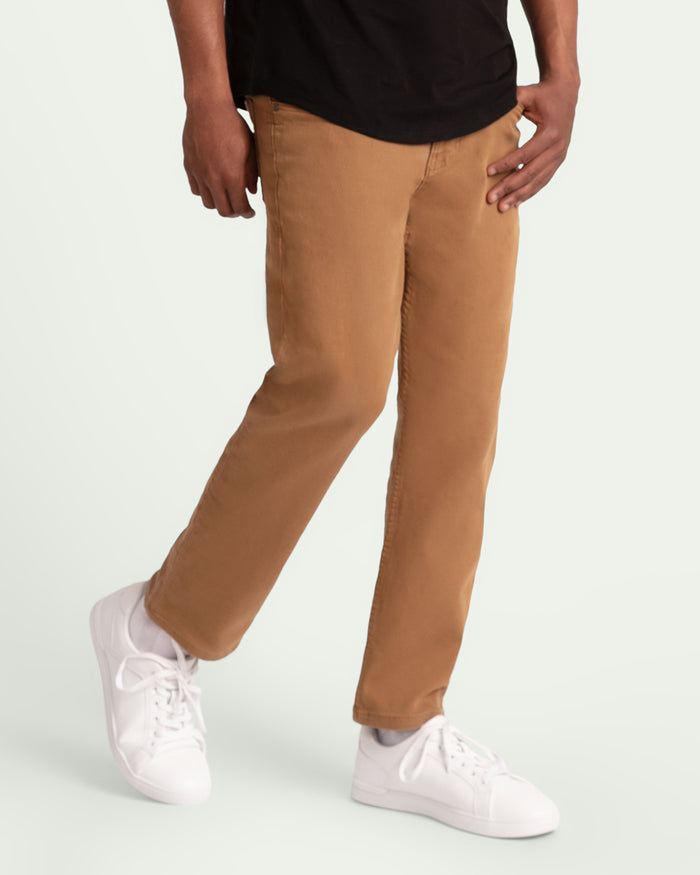 Man wearing tobacco brown slim fit pants with black shirt and white sneakers.