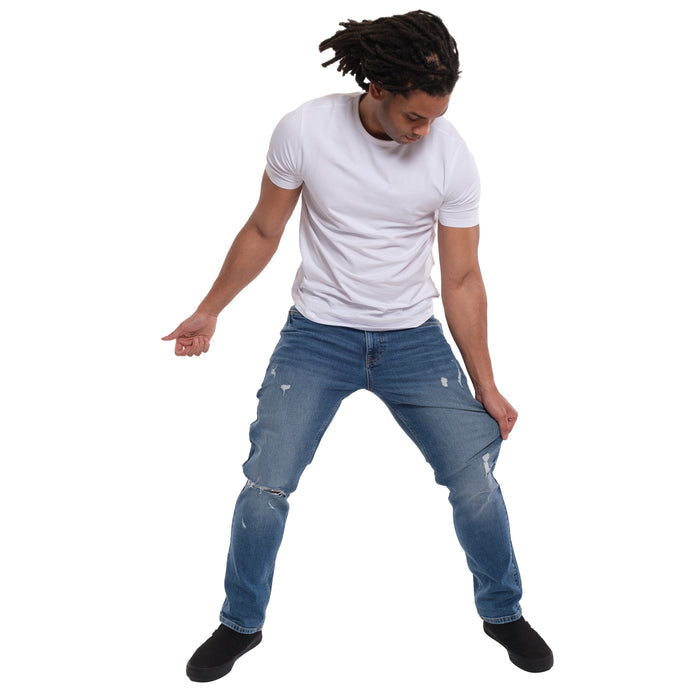 Man wearing white short-sleeve t-shirt and medium blue ripped jeans with distressing on thighs and knees.