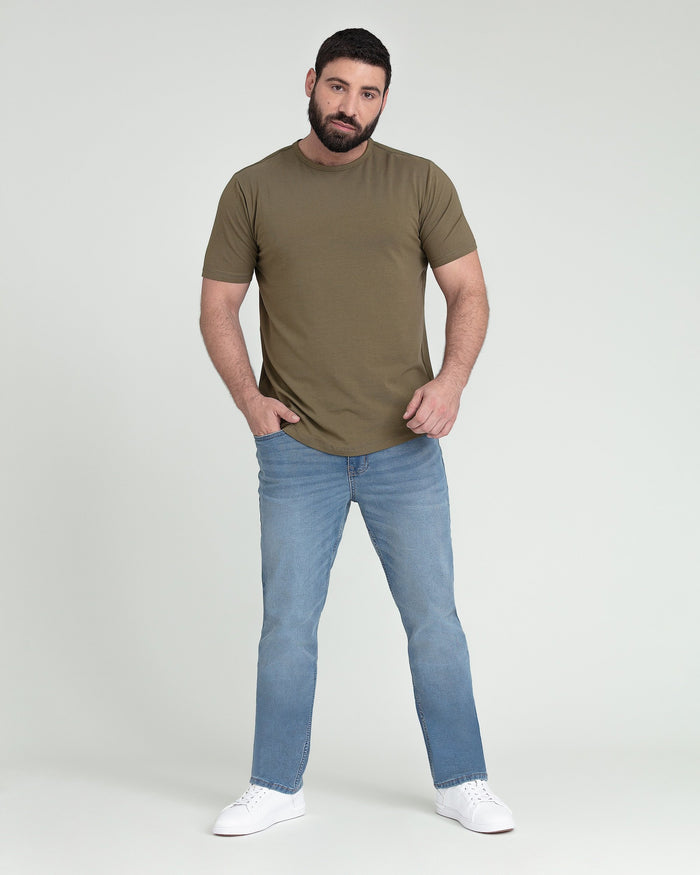 Man wearing olive-green short-sleeve t-shirt and light blue jeans with white sneakers.