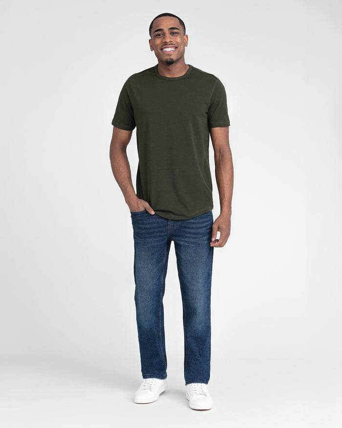 Man wearing olive green short-sleeve crewneck t-shirt and blue jeans with white sneakers.