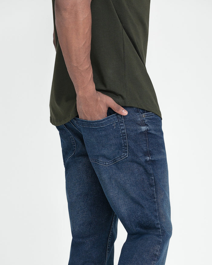 Dark blue jeans with tapered fit worn with olive green short-sleeve shirt.