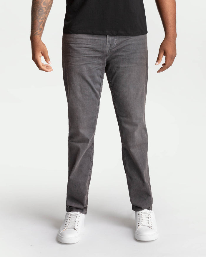 Man wearing grey denim jeans with black shirt and white sneakers.