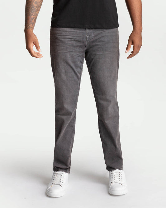 Man wearing grey denim jeans with black shirt and white sneakers.