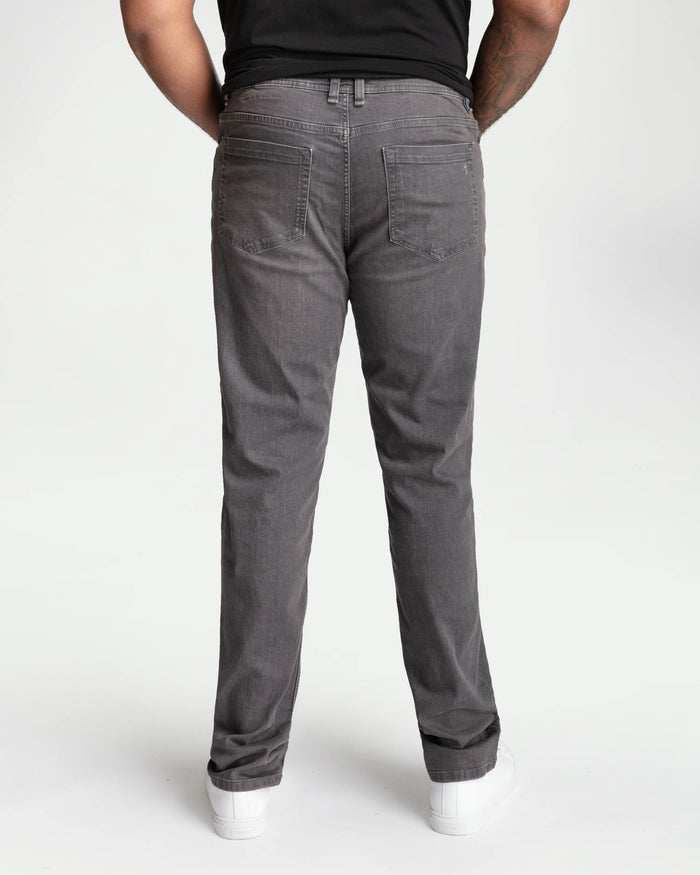 Man wearing grey denim jeans with back pockets, viewed from behind, paired with black t-shirt.