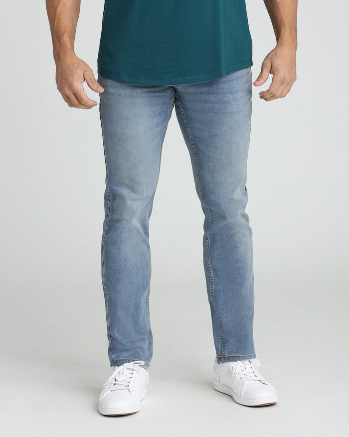 Man wearing light blue jeans with teal shirt and white sneakers.