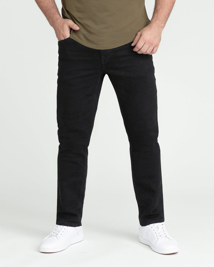 Man wearing olive-green t-shirt and black slim-fit jeans with white sneakers.
