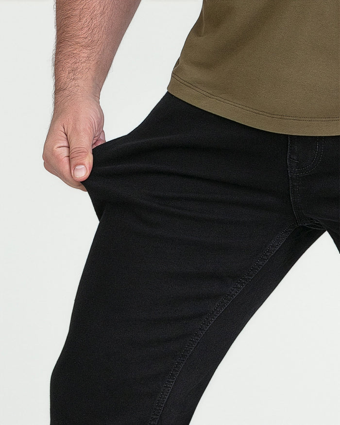 Man wearing olive-green shirt and black slim-fit jeans with visible waistband and inseam stitching.