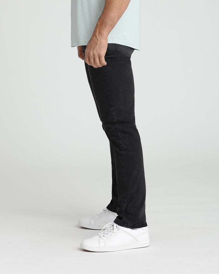 Man wearing faded black slim fit jeans with white sneakers and light gray t-shirt.