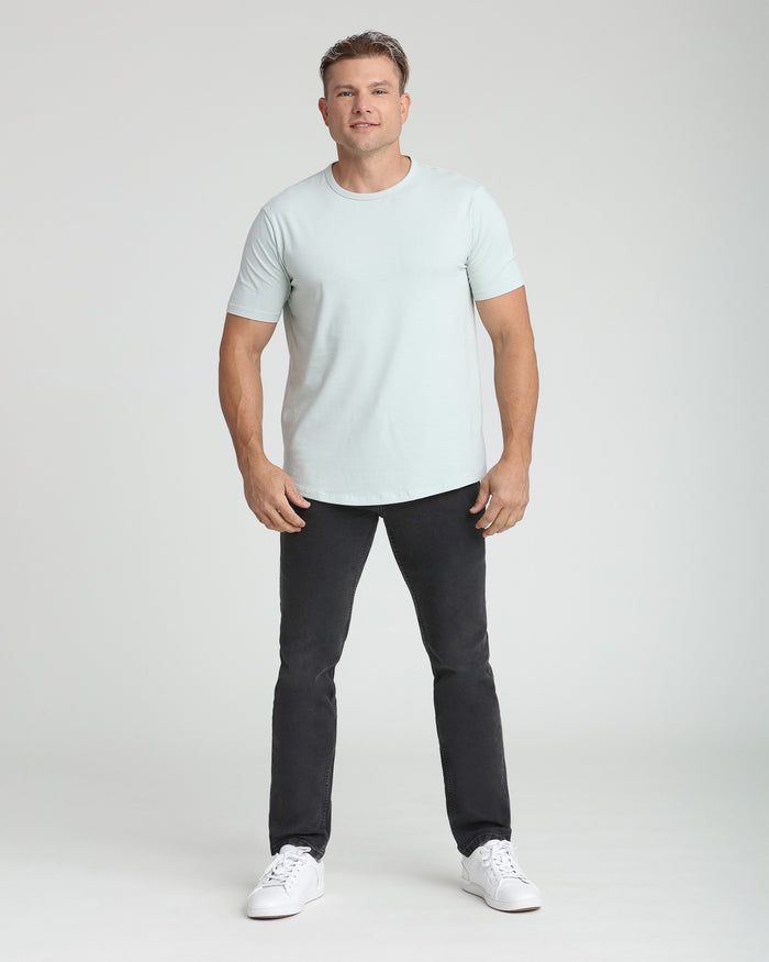 Man wearing light gray crew neck t-shirt and faded black slim fit jeans with white sneakers.