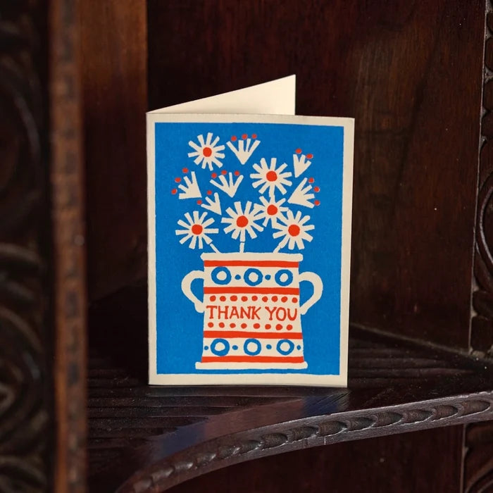 Greeting card with floral design and 'Thank You' text on a wooden surface
