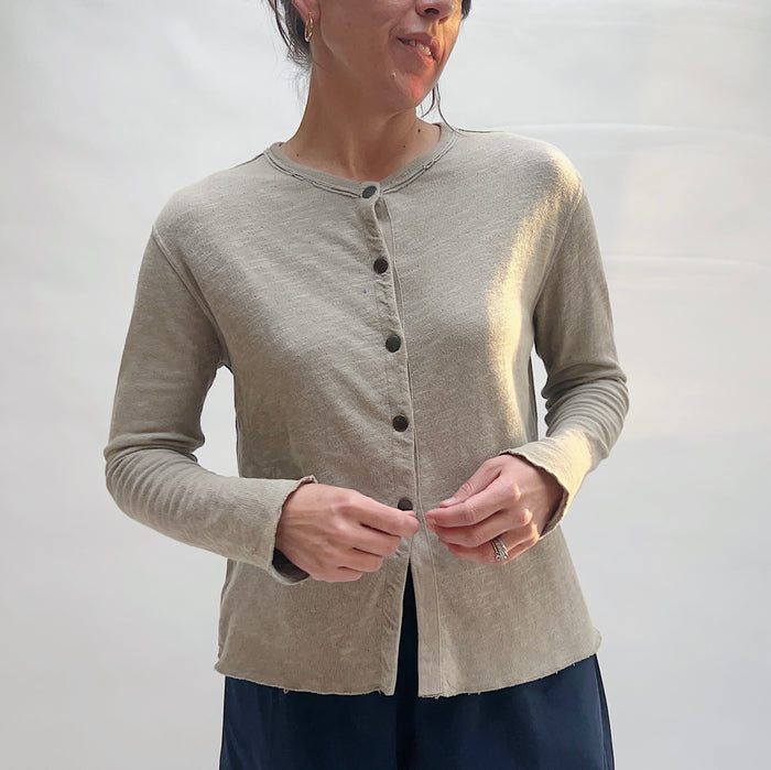 Close front view of model fastening North Star Base artichoke snap cardigan, showing snap-front closure detail, raw-edge neckline trim, and fitted body