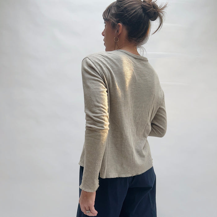 Back view of model wearing North Star Base artichoke snap-front cardigan, showing fitted silhouette, raw-edge hem, and long sleeves
