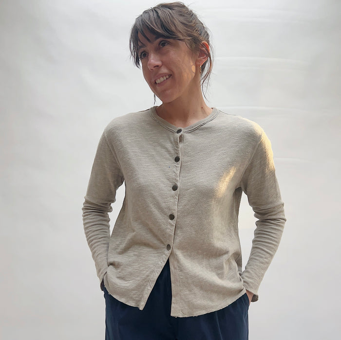 Full front view of model wearing North Star Base artichoke snap-front cardigan buttoned closed, showing crew neckline, snap placket, cropped length, and raw hem detail