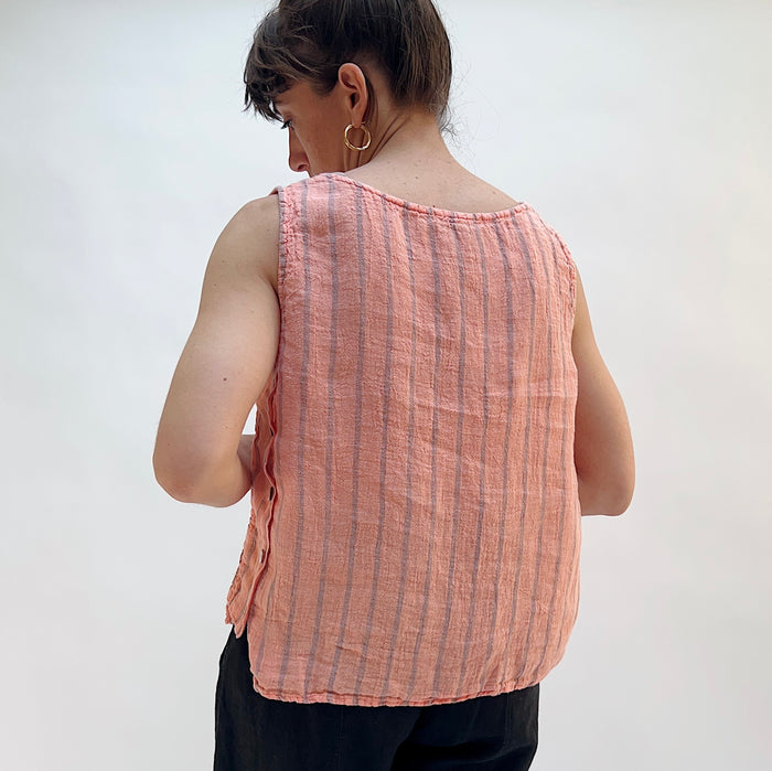 Person wearing a pink sleeveless shirt with vertical stripes against a plain background, viewed from the back