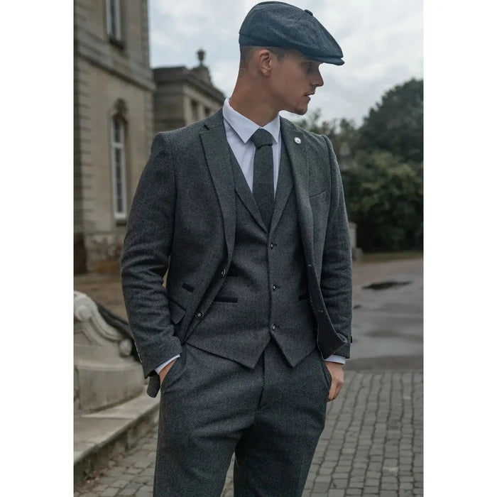 Close-up of men's grey tweed suit with herringbone pattern, tailored fit, featuring notch lapel, pocket details, and matching trousers.