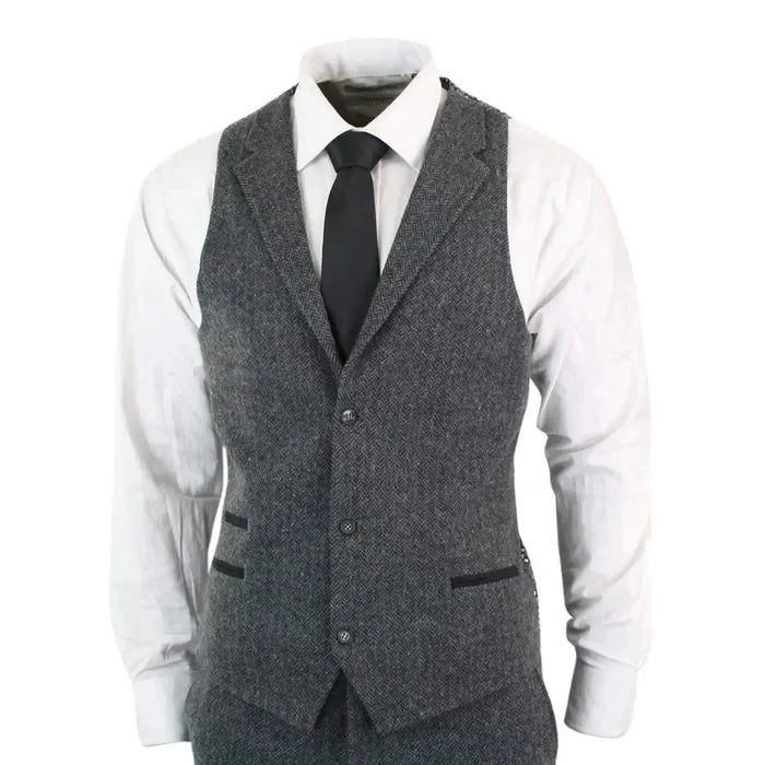 Men's grey herringbone tweed vest with black trim, worn over a white dress shirt and black tie, tailored fit for formal occasions.