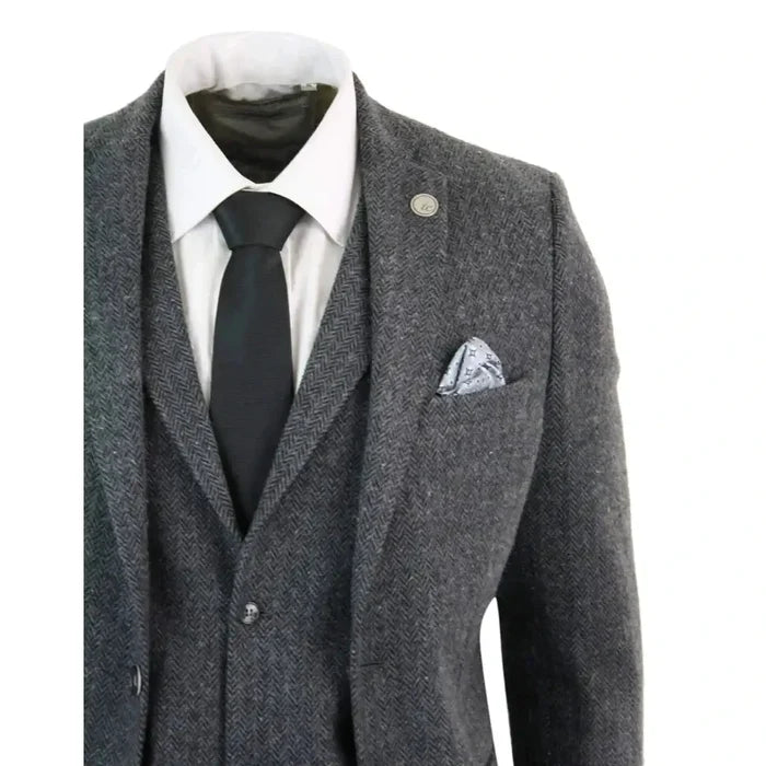 Men's grey and black herringbone tweed suit jacket with notch lapel, gold lapel pin, white shirt, black tie, and patterned pocket square, front view
