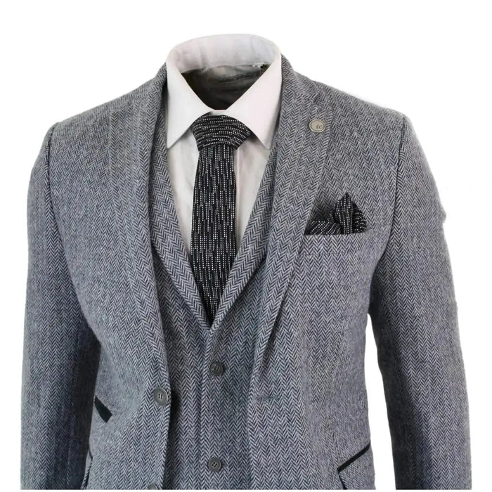 Men's grey herringbone tweed suit with tailored fit, styled with white shirt and black patterned tie, suitable for formal occasions