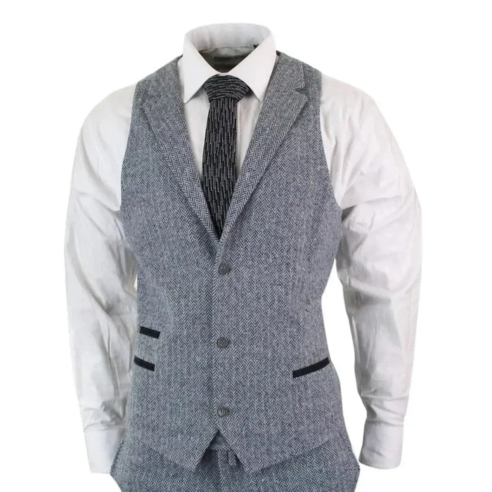 Men's light grey herringbone tweed 3-piece suit with tailored fit, includes blazer, waistcoat, and trousers, paired with a white shirt and black patterned tie.
