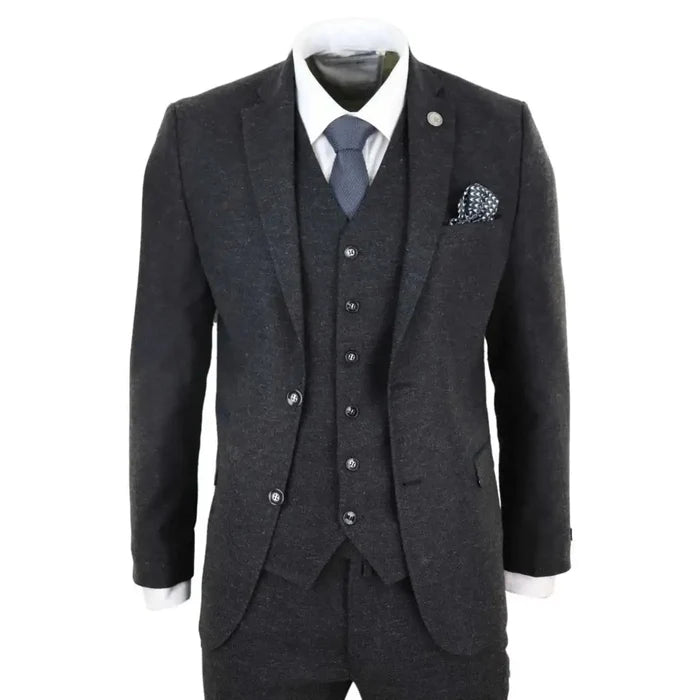 Men's dark grey wool tweed suit with tailored blazer, vest, and white shirt, styled with a blue tie and pocket square for formal wear.