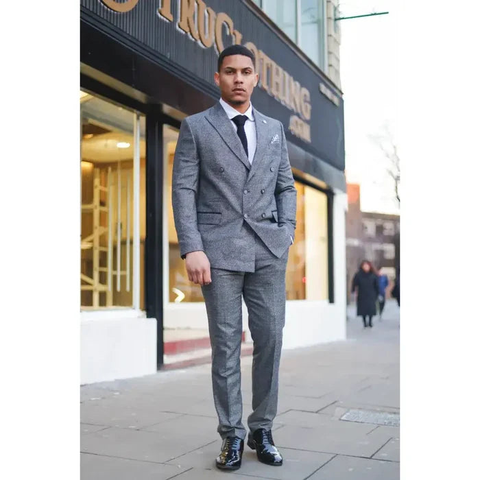 Man wearing a stylish grey plaid double-breasted suit with a slim fit, white shirt, black tie, and polished black shoes for business or events.